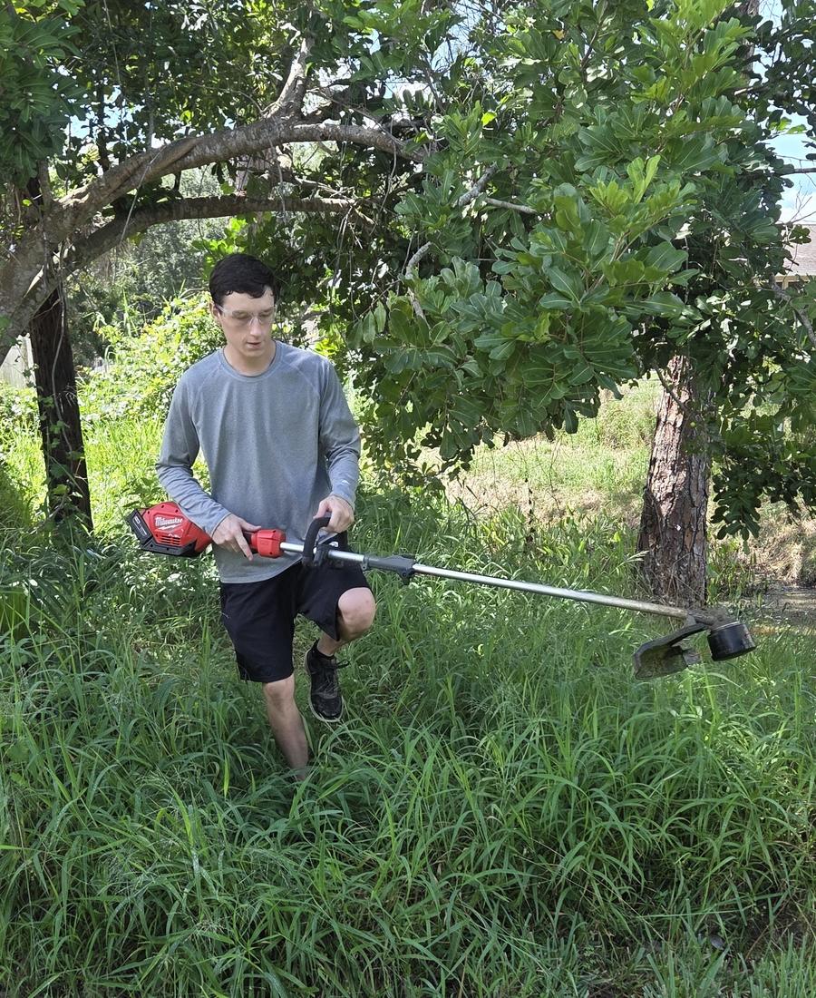 Ronnie, owner of Aiden’s Lawn & Landscape, clearing an overgrown yard in Sebastian, FL